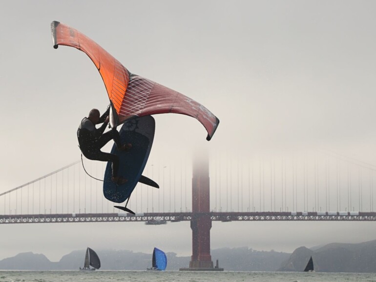 ean Rathle, @streetsailing, takes to the air on his wing foil as Cal and Stanford spinnakers fly in the background. Photo by Bryan McDonald