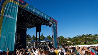 A crowd of people raise their arms toward the stage of Mill Valley Music Festival