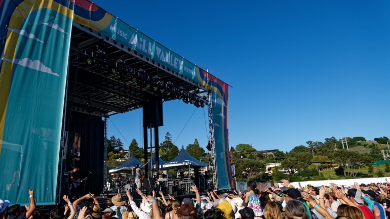A crowd of people raise their arms toward the stage of Mill Valley Music Festival