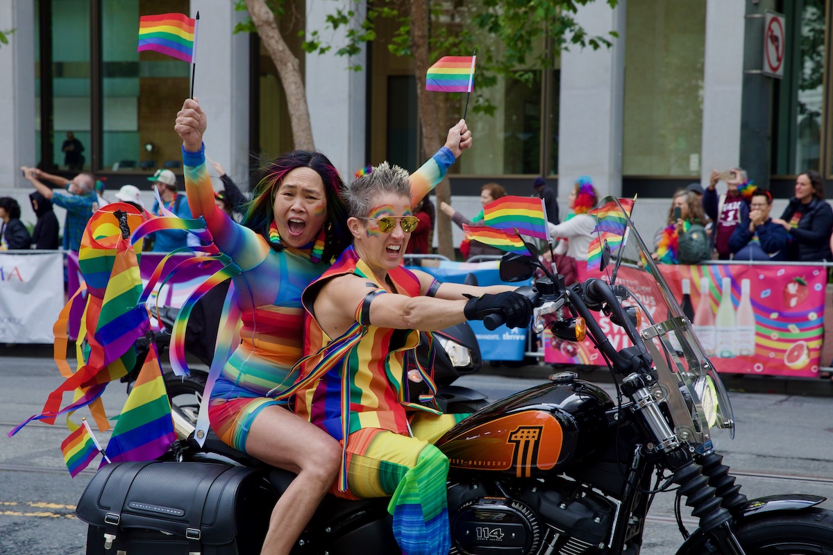 Two women dressed in rainbow ride a motorbike in the San Francisco Pride Parade June Event