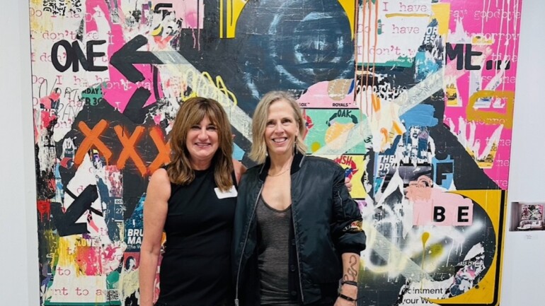 Two women stand in front of modern art piece at ICB Open Studio, a community event in Marin