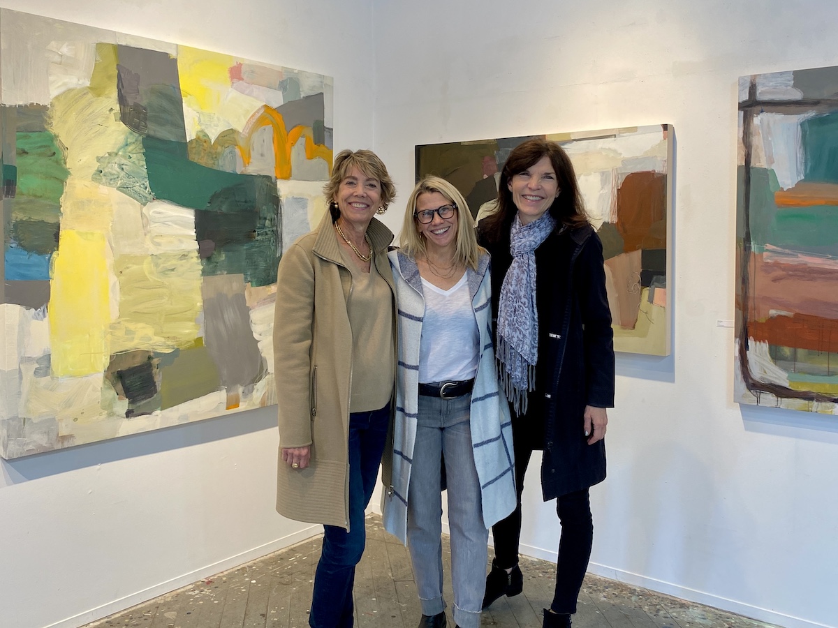 Three women stand in front of paintings at ICB Winter Open Studio