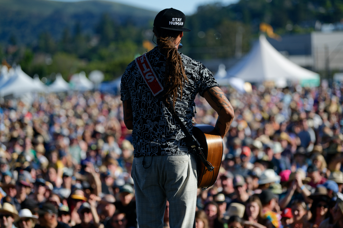 Performer stands facing a large audience at Mill Valley Music Festival