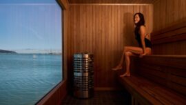 A woman sitting in a sauna overlooking the bay.