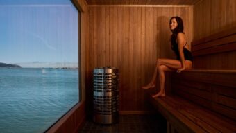 A woman sitting in a sauna overlooking the bay.