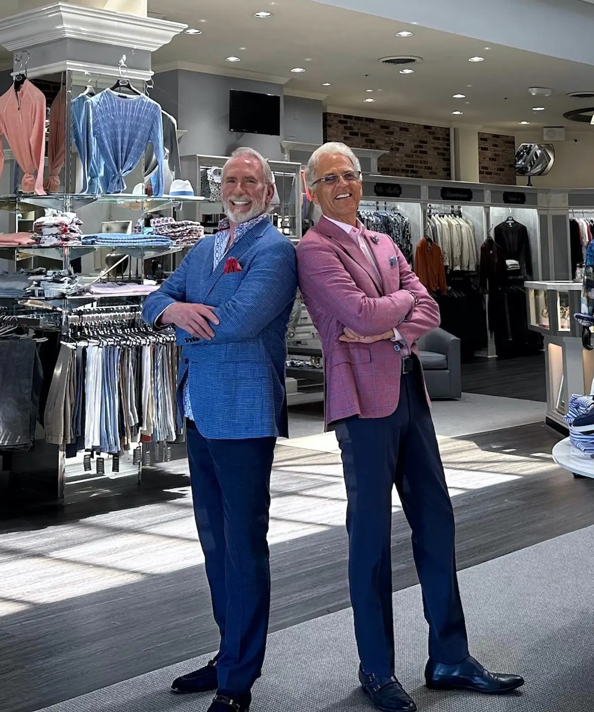 Owners of Gene Hiller Menswear stand back-to-back