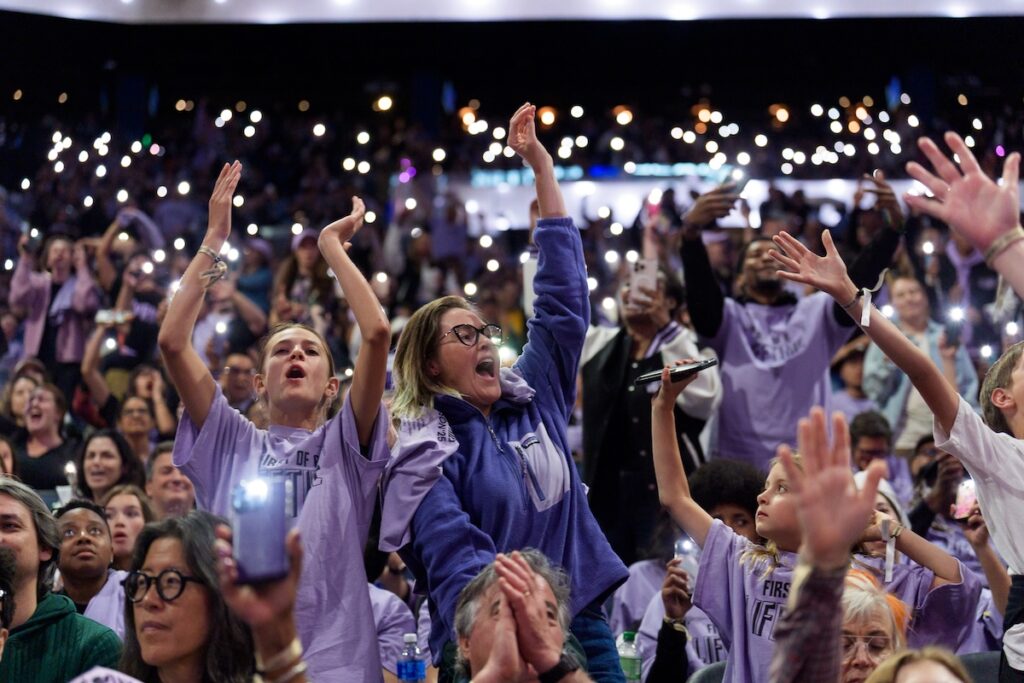 A crowd of cheering fans wearing purple and holding cell phones up at Golden State Valkyries game
