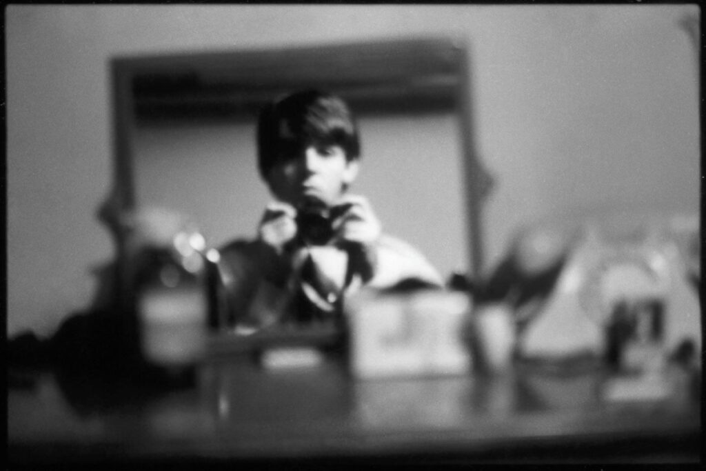 A young Paul McCartney taking a photo of himself in a mirror