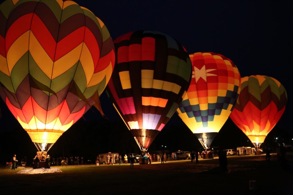 Colorful hot air balloons illuminated by their fires in the dark