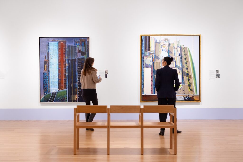 Two museum goers stand in front of Wayne Thiebaud paintings at the Legion of Honor in San Francisco