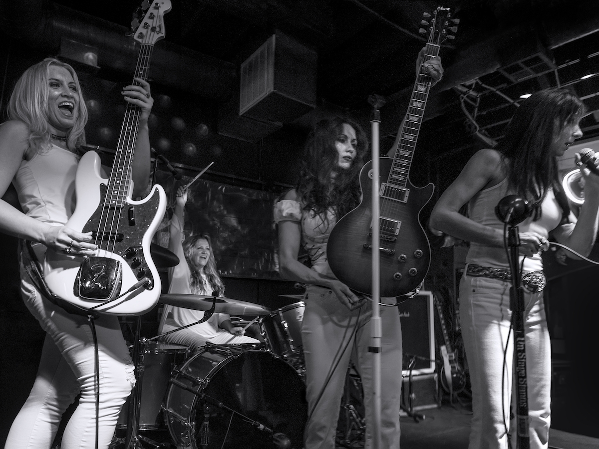 Four-piece rock band Zepparella playing on stage in black and white photo