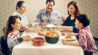 Five people, including two children, parents and a grandmother, sit around a dinner table.