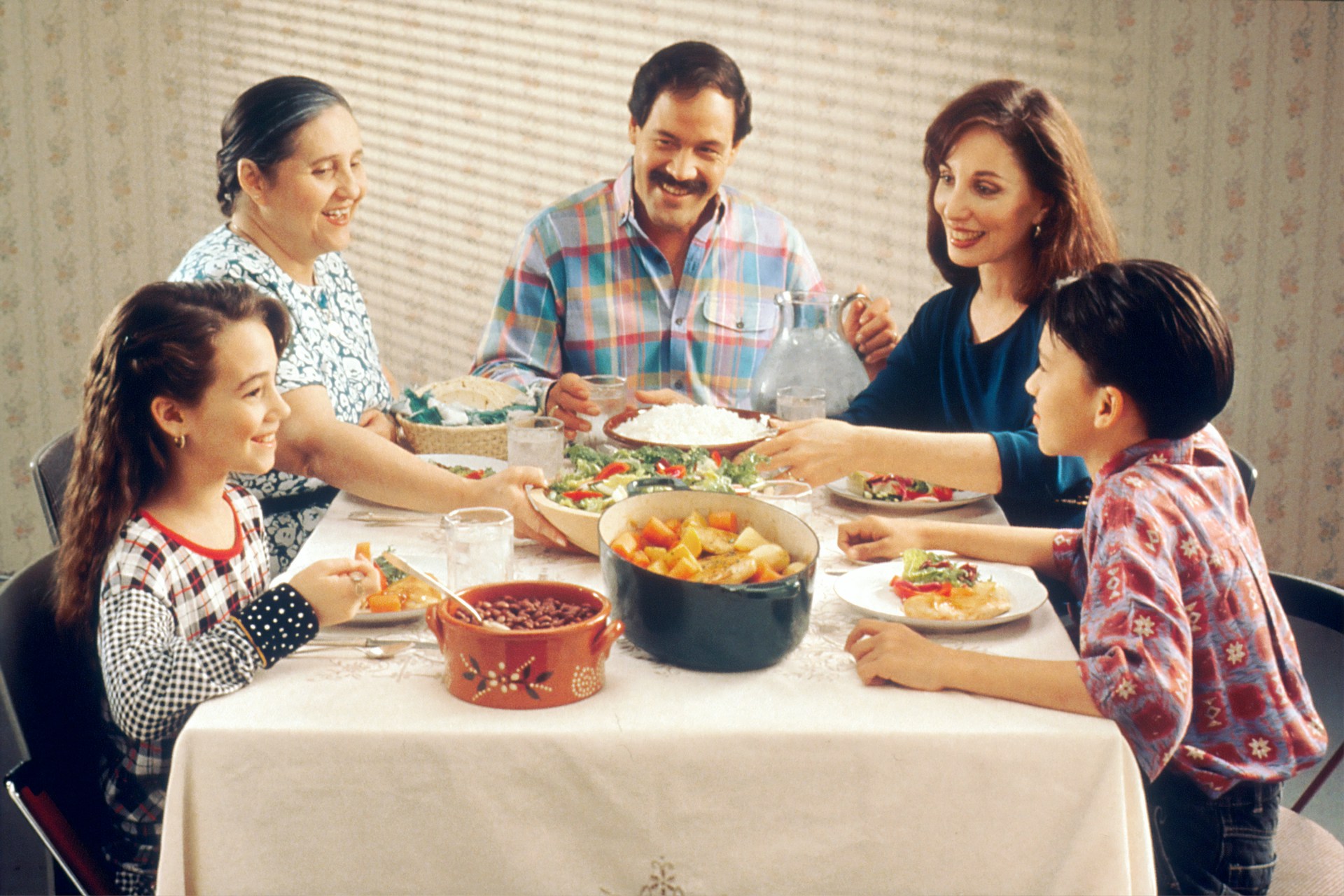 Five people, including two children, parents and a grandmother, sit around a dinner table.