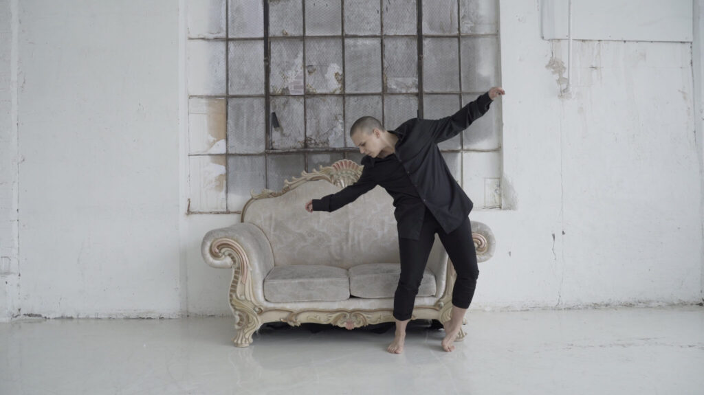 A person dancing in front of a couch in the film "Love More" directed by Hayden Frederick, featuring in San Francisco's Transgender Film Festival