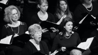 Black and white image of chorus singers, dressed in black and holding sheet music, part of Marin Oratorio's December concert