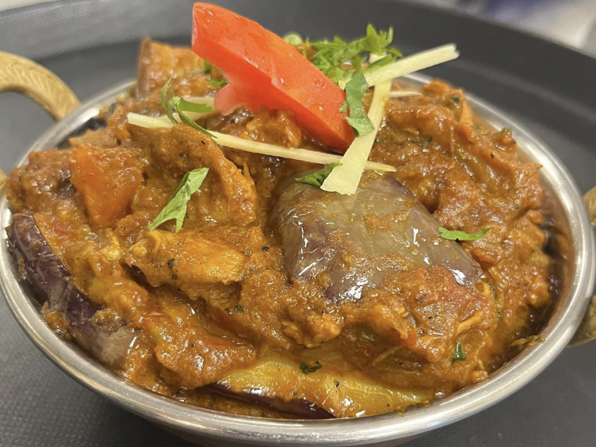 A bowl with marinated meat, topped with shredded lettuce and a piece of tomato.