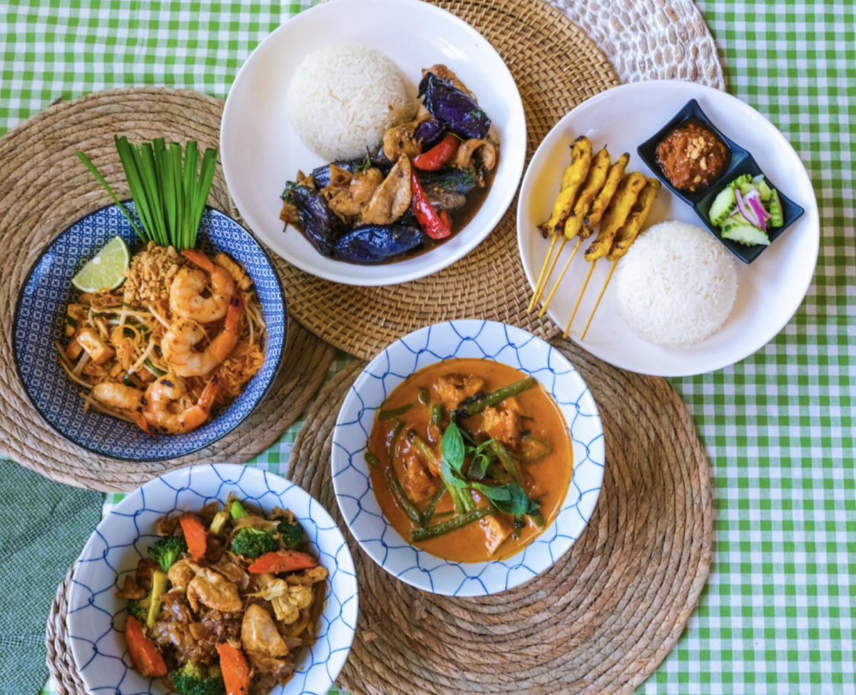 Bowls with various Thai food including stir fry, an orange soup, rice, shrimp and kebabs.