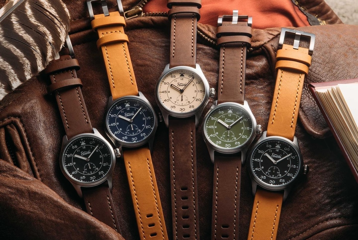 Five watches with brown bands and assorted colored faces.