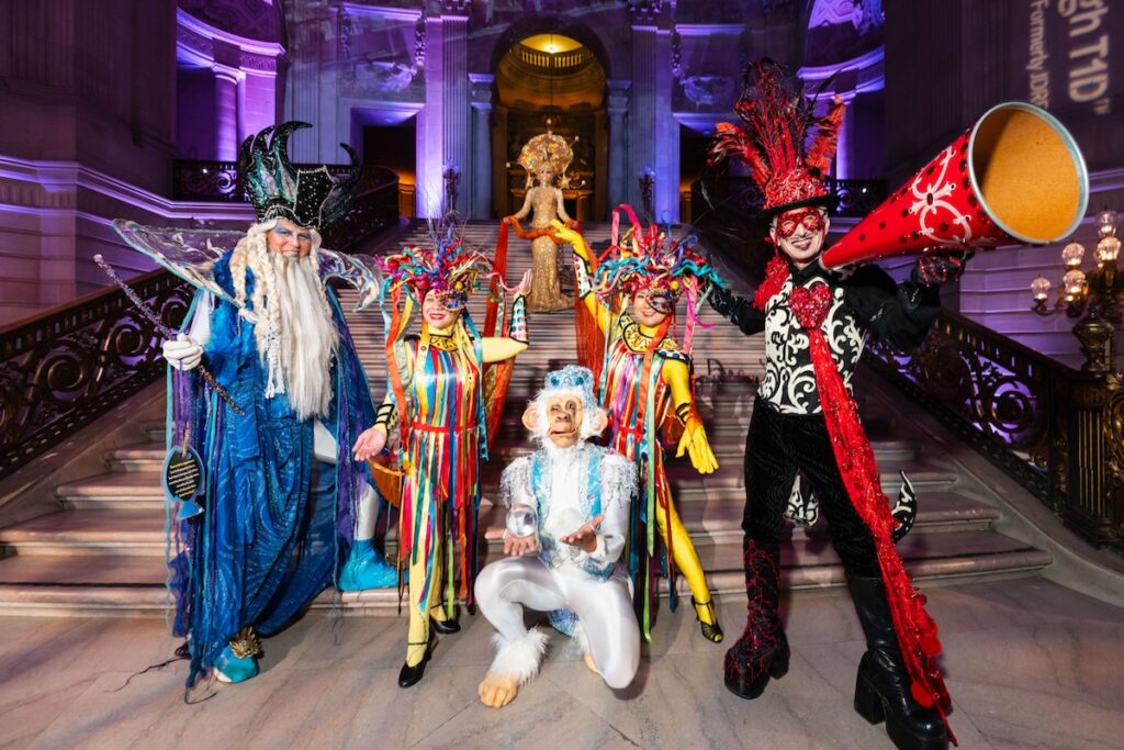 A group of people wearing colorful, fancy circus-inspired costumes.