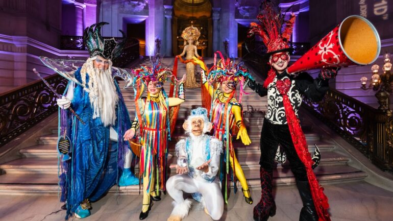 A group of people wearing colorful, fancy circus-inspired costumes.