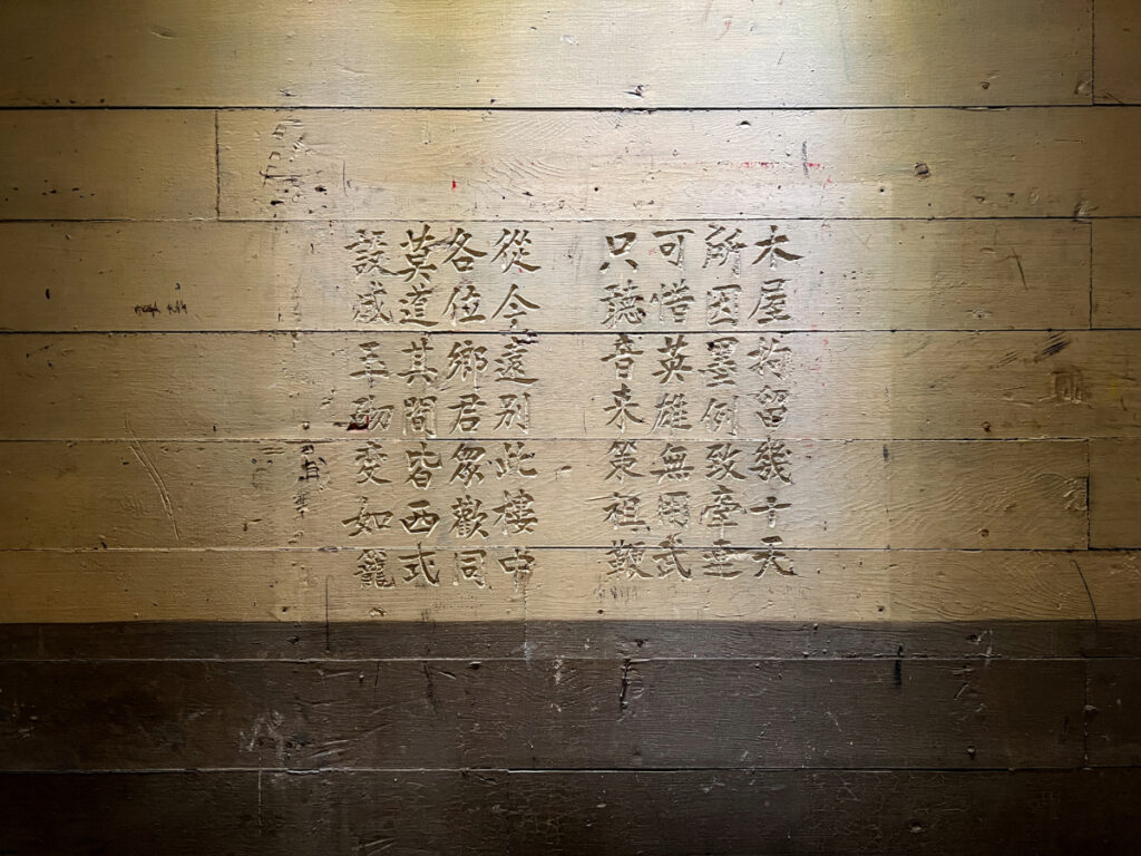 Chinese characters carefully carved into aged wooden walls, capturing the emotions of detained immigrants.