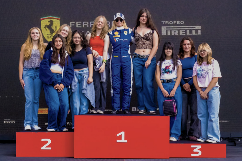A group of young girls stand on a red three-tiered podium.