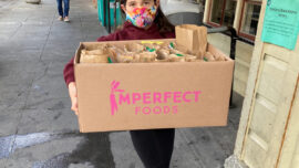 In 2020, 9-year-old Mia Slowe carries a box of homemade bag lunches on the sidewalk outside St. Vincent de Paul in San Rafael, volunteering for those facing food insecurity.