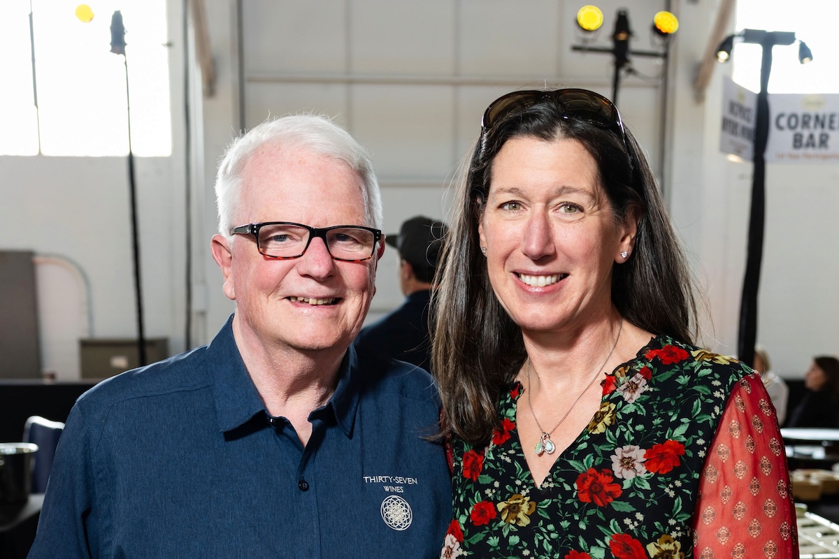 A man wearing a blue button down and glasses with a woman wearing a floral blouse.