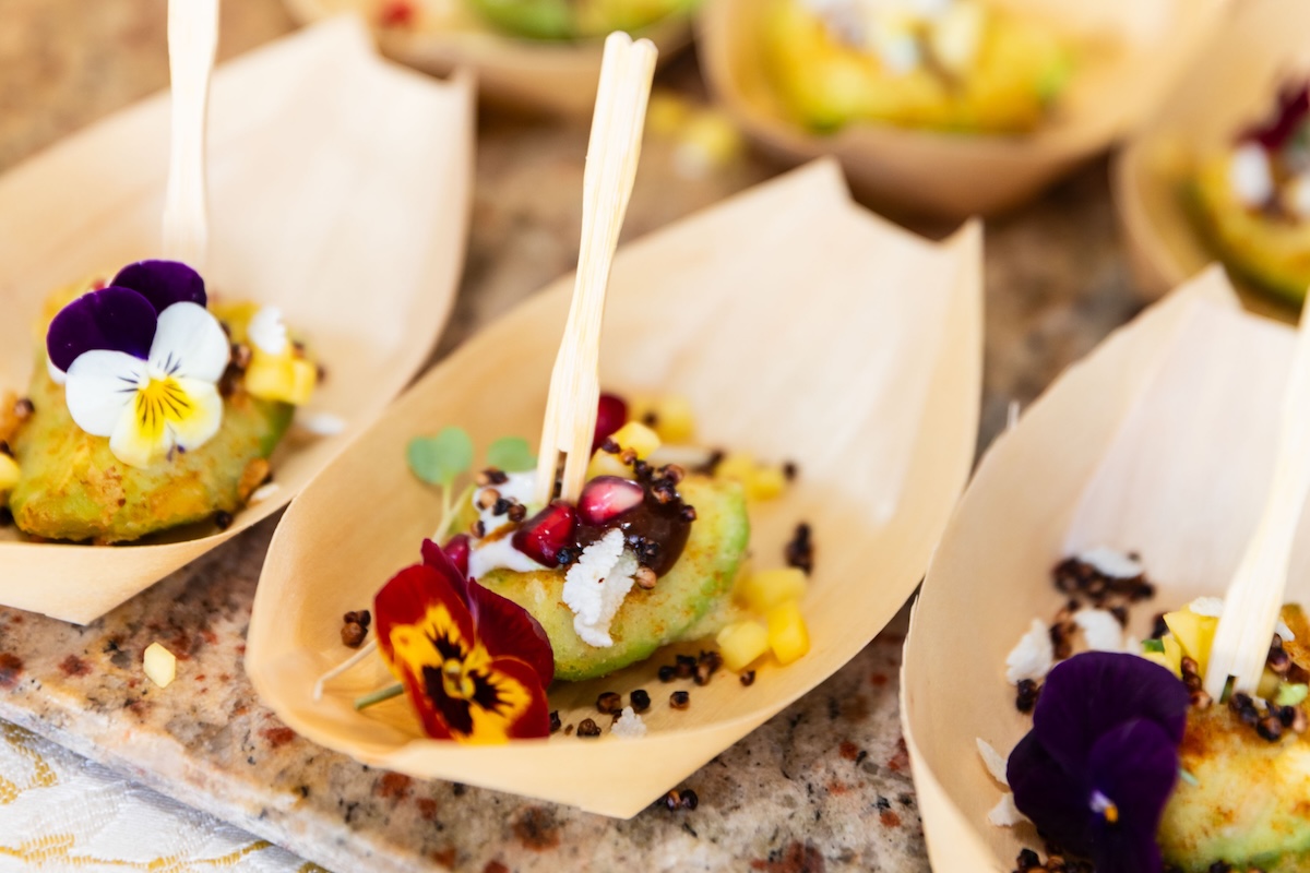 Mini boats of avocado topped with pomegranate seeds, edible flowers, microgreens and more.