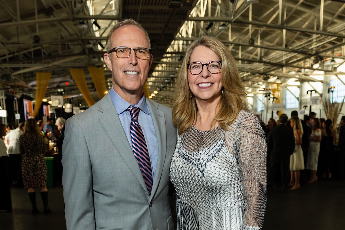 A woman wearing a white and silver dress with a man wearing a gray suit and pink striped tie.