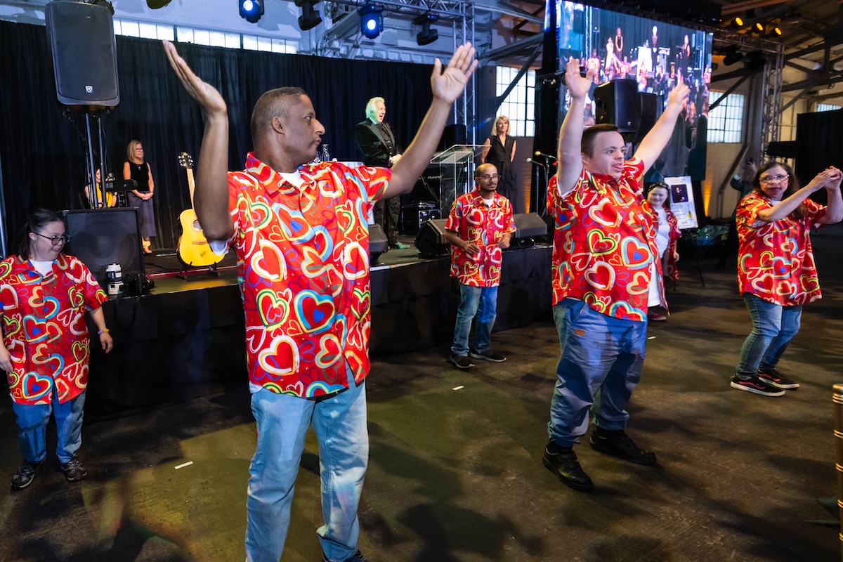 A group of people wearing red button down with rainbow hearts.