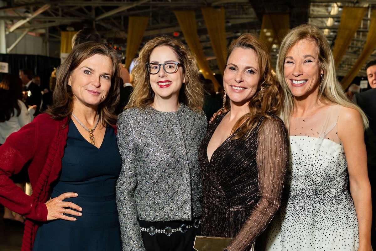 A group of four women wearing fancy attire.