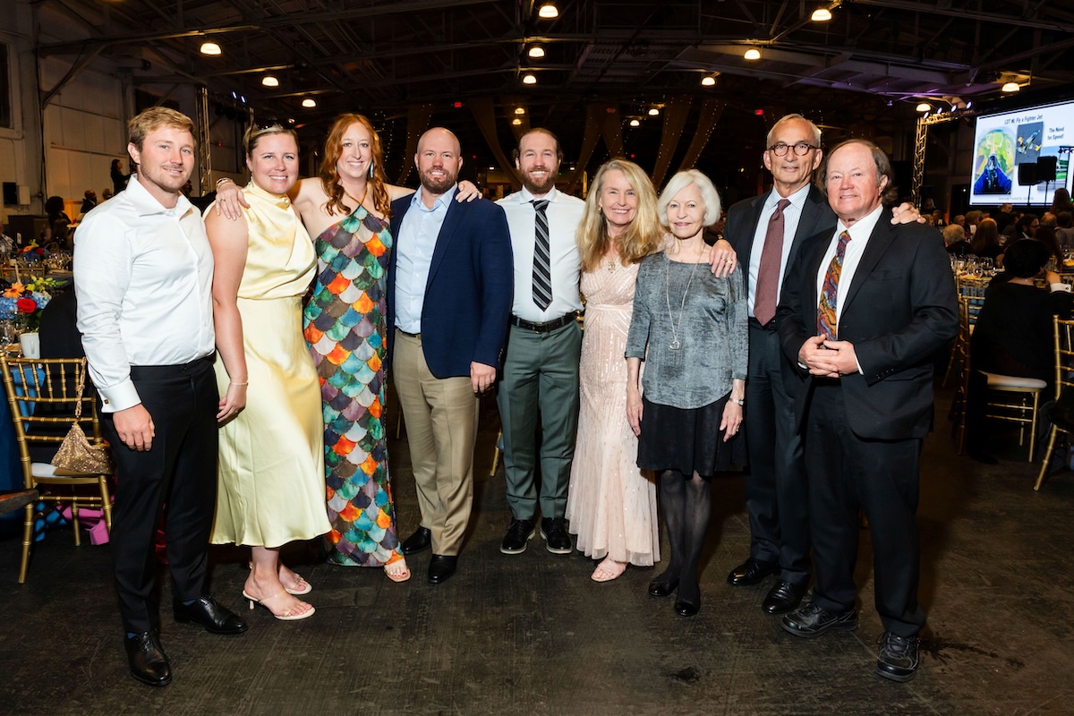 A group of nine people wearing cocktail attire.