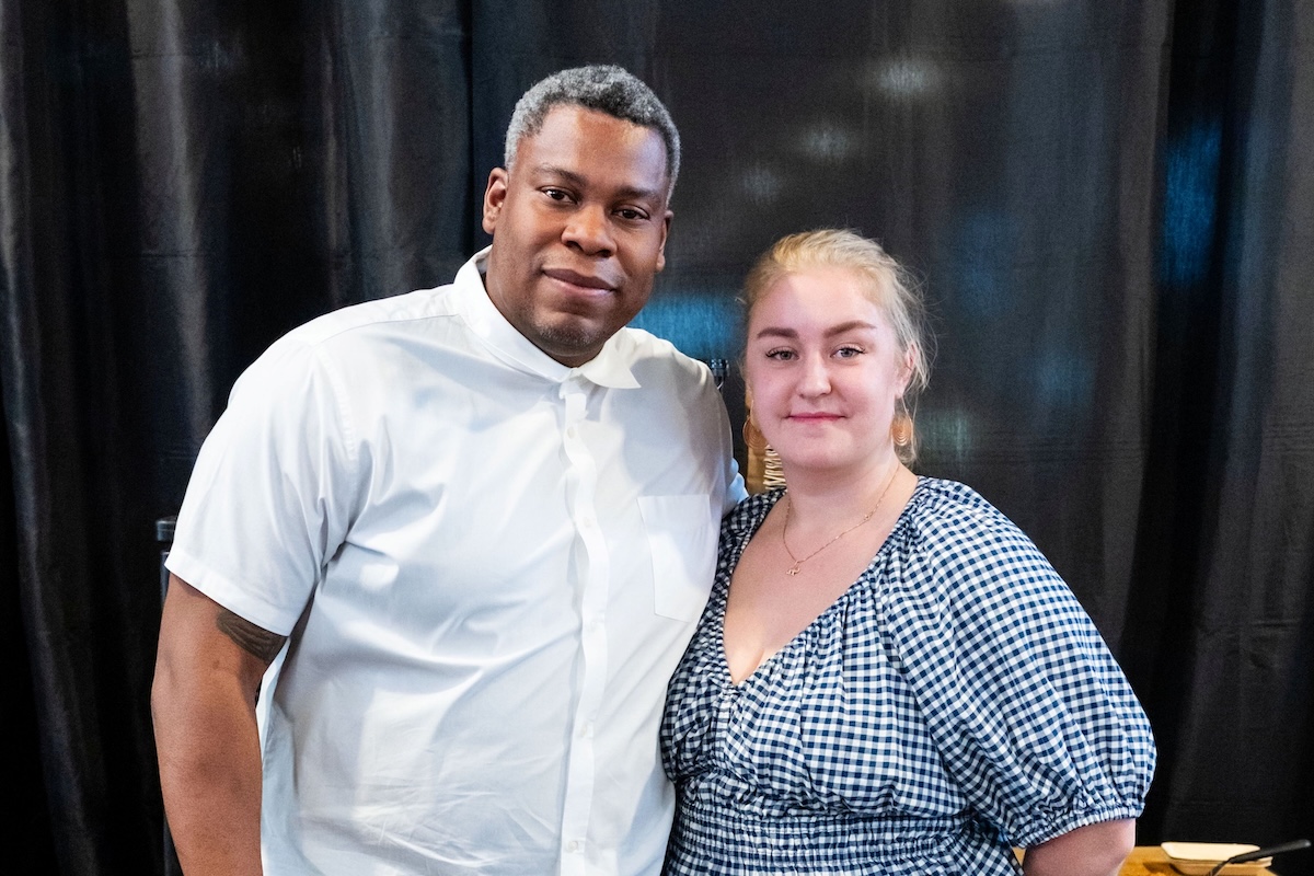 A man in a white button down stands with a woman in a blue gingham blouse.