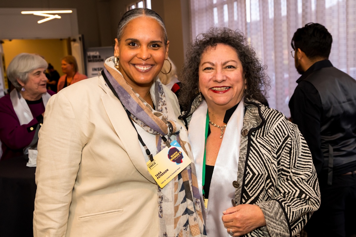 Two women standing together wearing yellow badges.