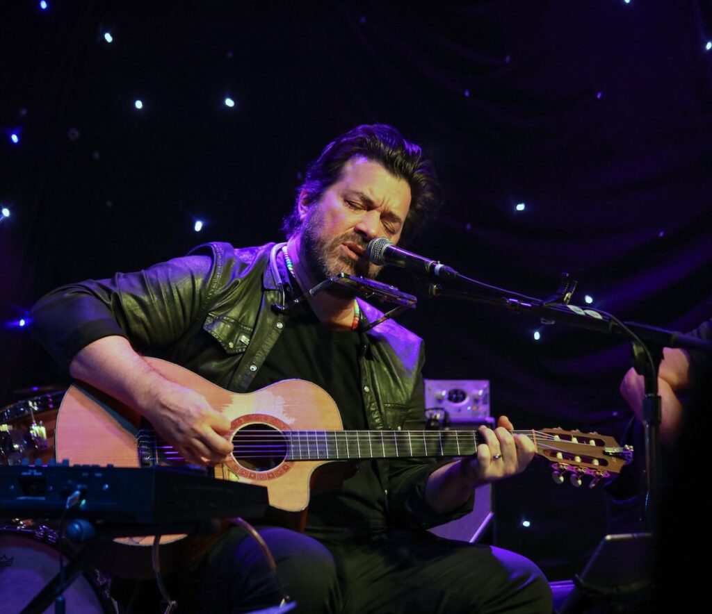 Bob Schneider plays guitar on stage