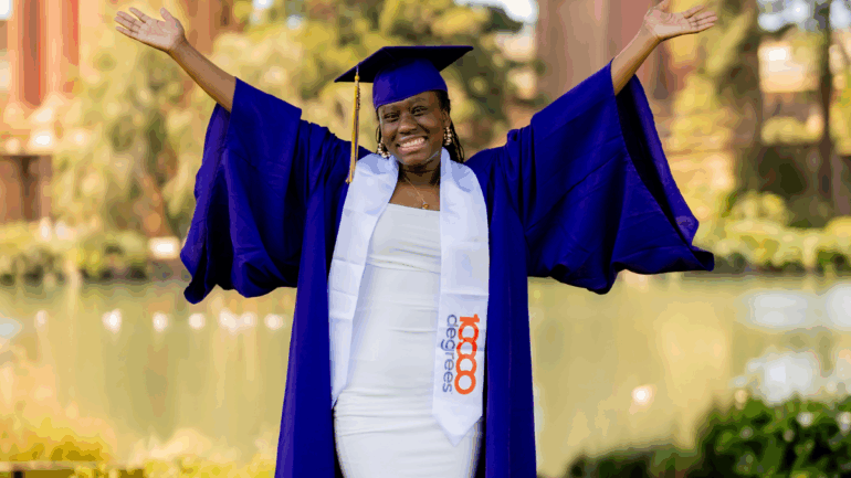 A new graduate student standing with her arms spread out smiling.