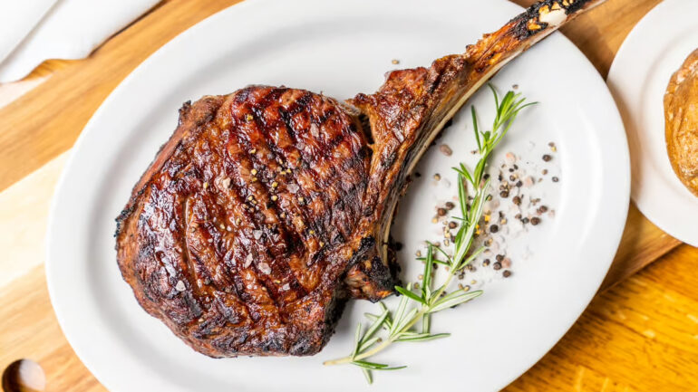 An aerial shot of meat on the bone garnished with a sprig of rosemary.