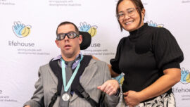 A woman patting a man with a disability on the back and smiling.