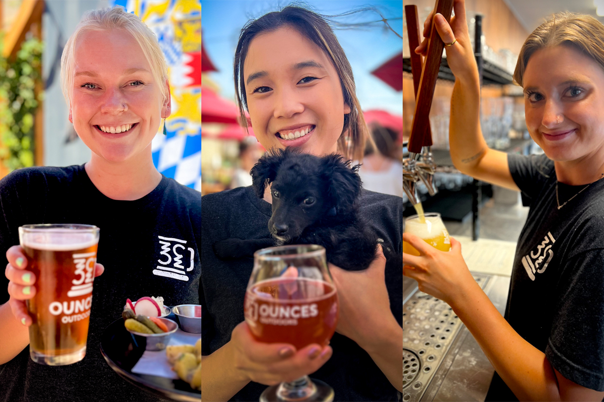 Three girls pose for photos, one holding a dog and them all holding a glass of beer.