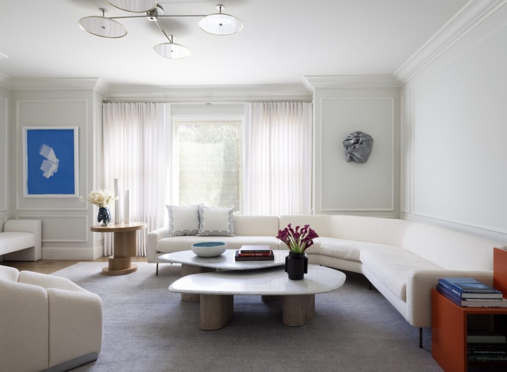 A modern white couch in a mostly white living room.
