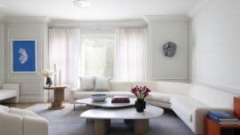 A modern white couch in a mostly white living room.
