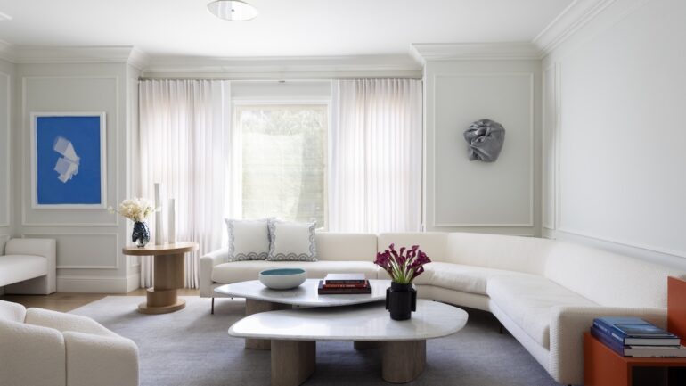 A modern white couch in a mostly white living room.