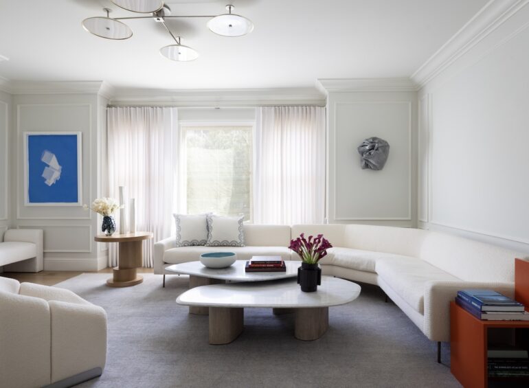 A modern white couch in a mostly white living room.