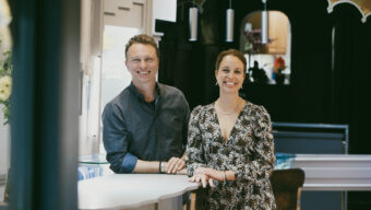 A man and a woman standing in a jewelry store smiling.