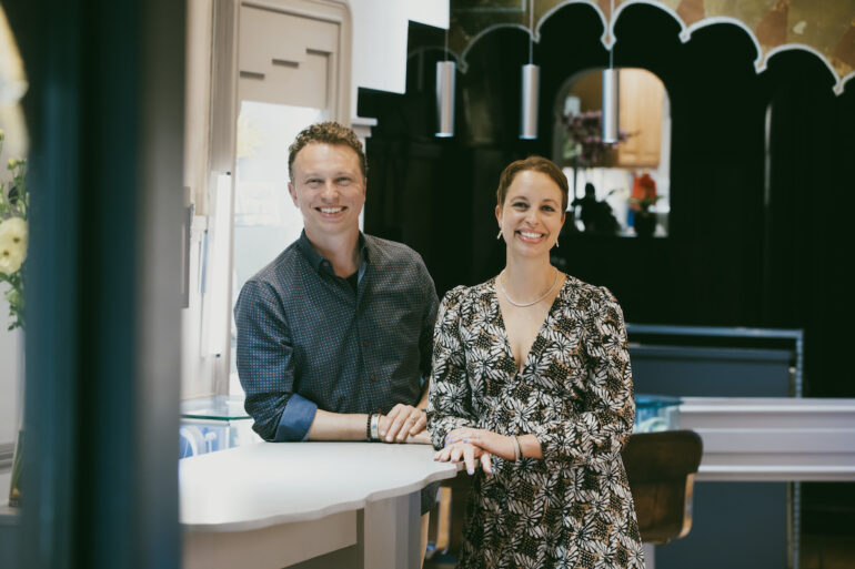 A man and a woman standing in a jewelry store smiling.