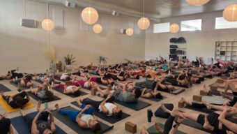 A large group of people lying on yoga mats.