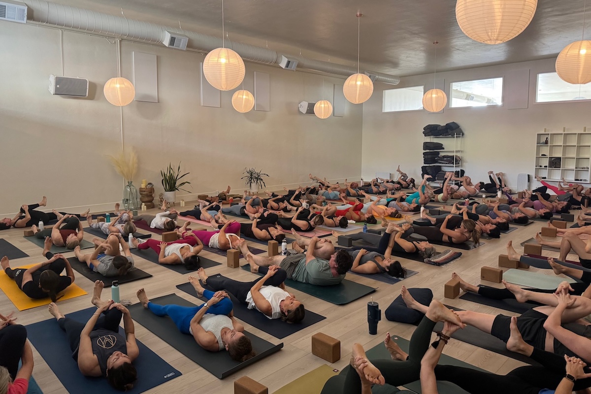A large group of people lying on yoga mats.