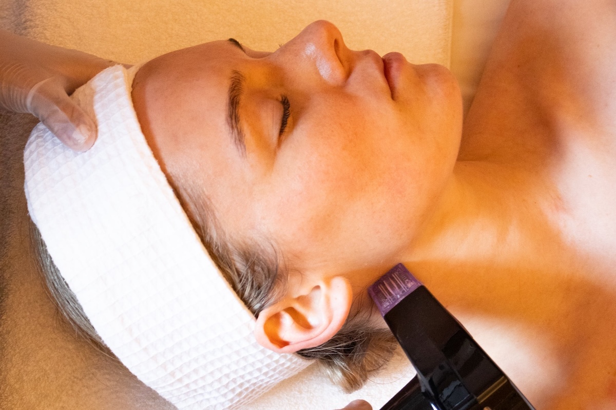 A woman laying with her eyes closed wearing a white headband across her forehead.