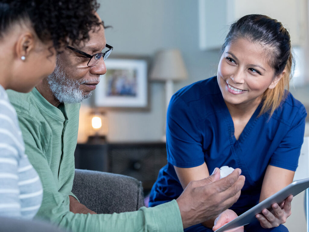 A nurse and patient interact through a tablet, highlighting the use of technology in healthcare communication.